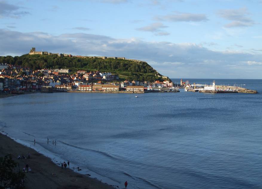 Англия, Панорамен изглед към централната част на Скарбъроу с крепостта на хълма над града, пристанището (в дясната част на снимката) и плажът (долу в ляво)
