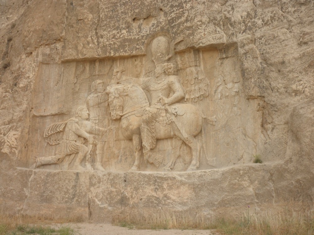 Триумфалният релеф от Персеполис с шах Шапур I на кон и пленения и на колене римски император Валериан I след битката при Едесса в 260 г.
