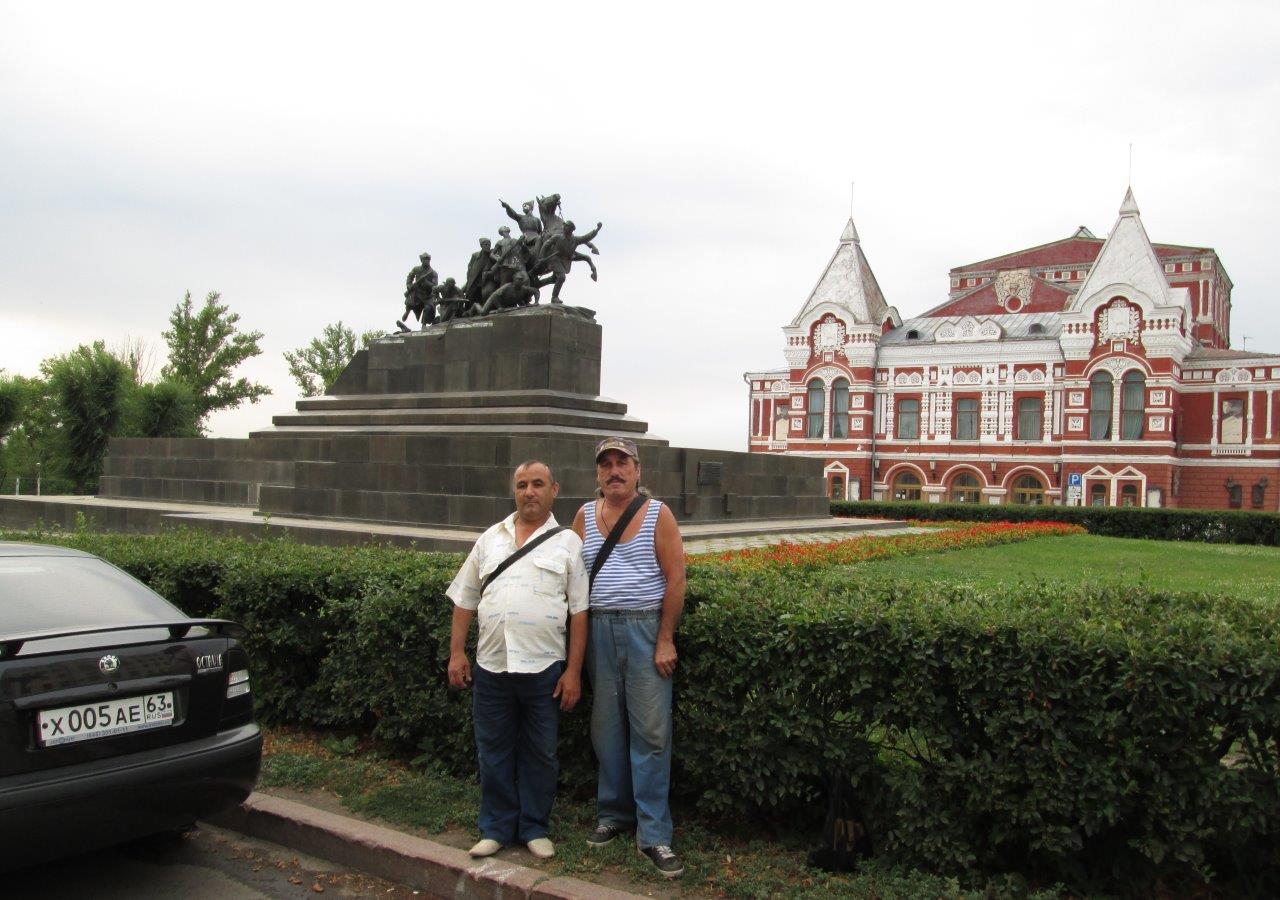 Двамата строители от Узбекистан на фона на паметника на Чапаев и Драматичния театър
