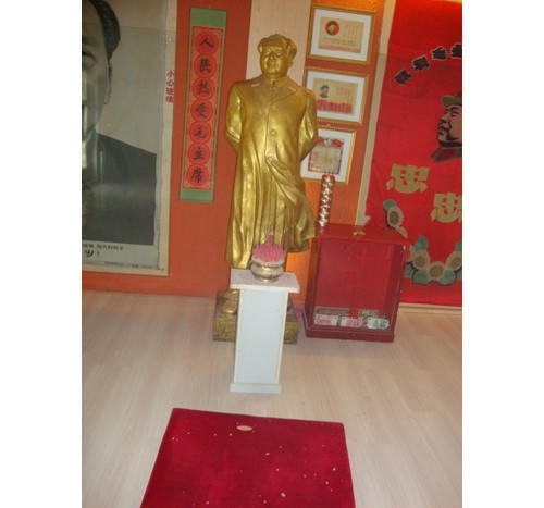 Статуята на Мао със свещи и постелка за молитви